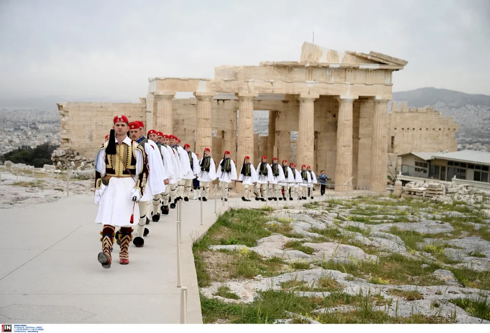a group of men in uniform walking in front of a stone building